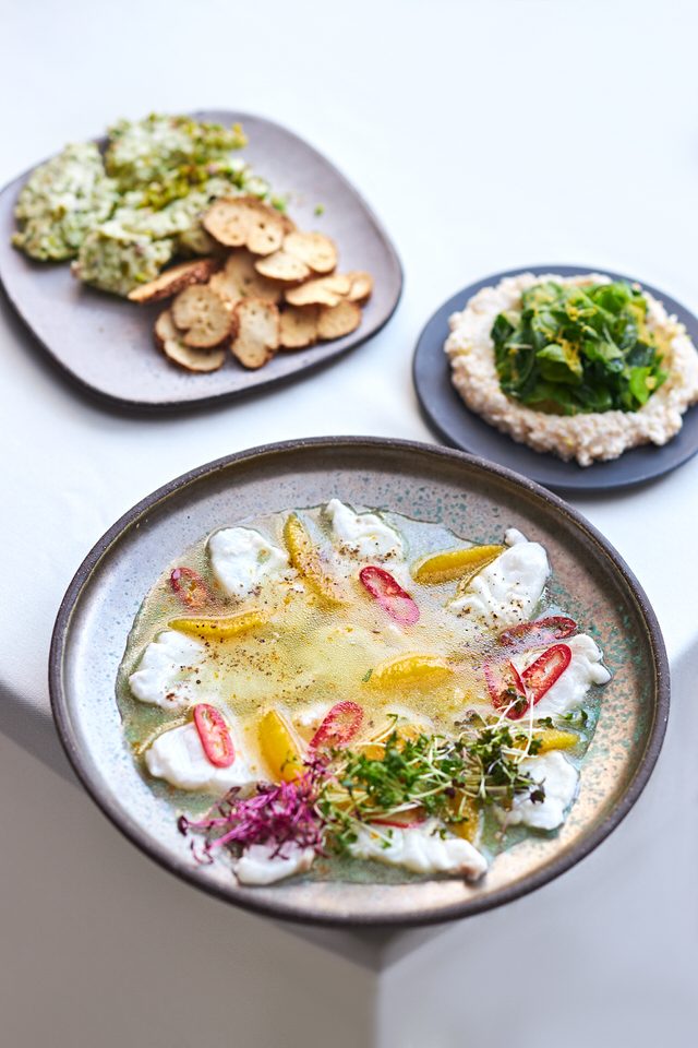 Pencereden gelen yumuşak gün ışığında üç seramik tabaklı restoran masası