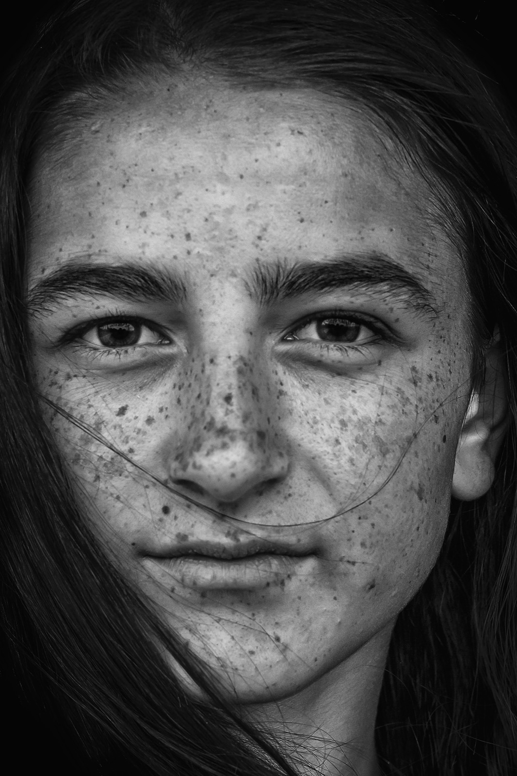 Çilli ve koyu saçlı genç bir kadının doğrudan kameraya bakan yakın portresi — Sefa Yamak'tan sokak fotoğrafı, İstanbul serisi.